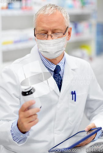 Image of old apothecary in mask with tablet pc at pharmacy