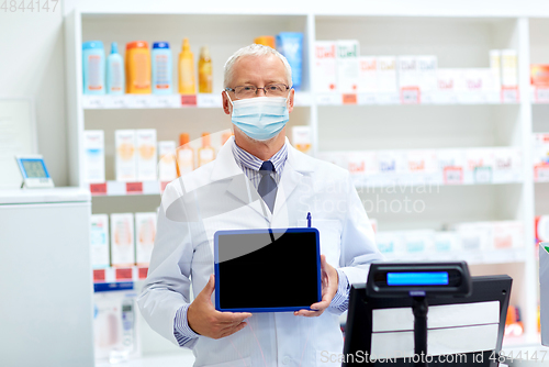 Image of old apothecary in mask with tablet pc at pharmacy