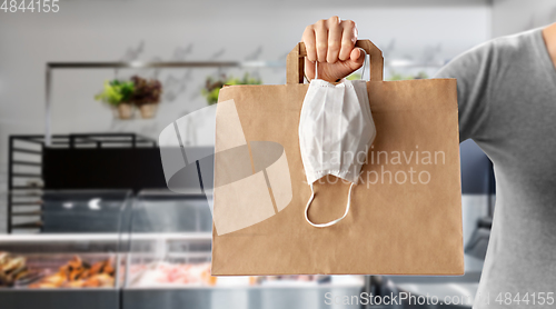 Image of woman with food in bag and mask at grocery store