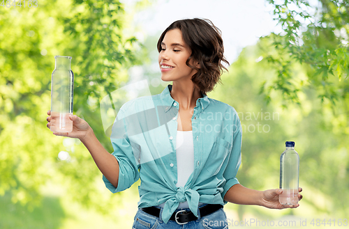 Image of smiling young woman comparing bottles of water