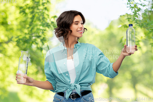 Image of smiling young woman comparing bottles of water