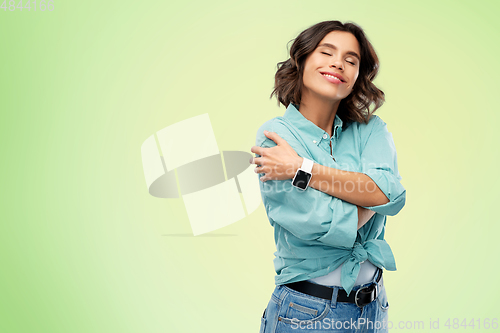 Image of smiling woman with smart watch hugging herself