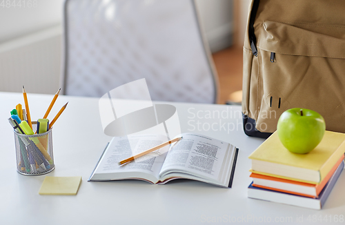 Image of books, apple and school supplies on table at home