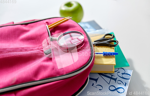 Image of backpack with books, school supplies and apple