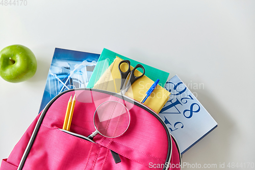 Image of backpack with books, school supplies and apple