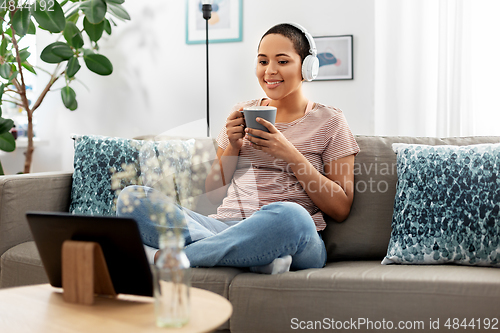 Image of woman with tablet pc drinking coffee at home