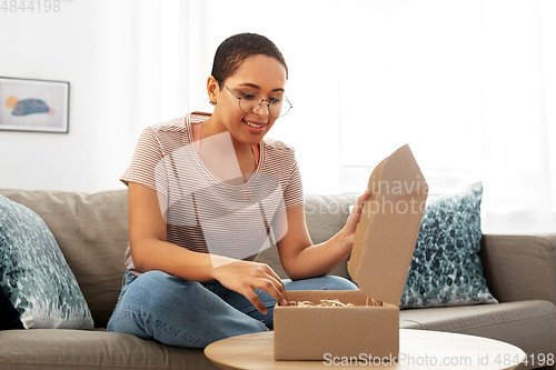 Image of african american woman opening parcel box at home