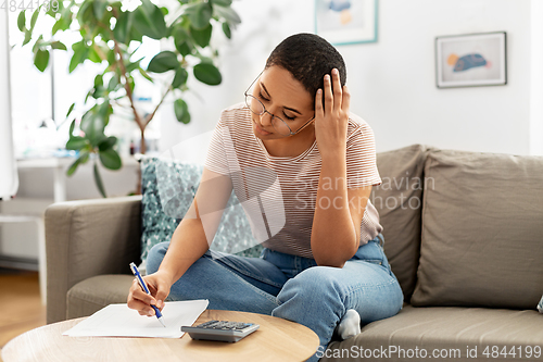 Image of african woman with papers and calculator at home