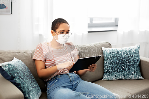 Image of woman in medical mask with tablet pc at home