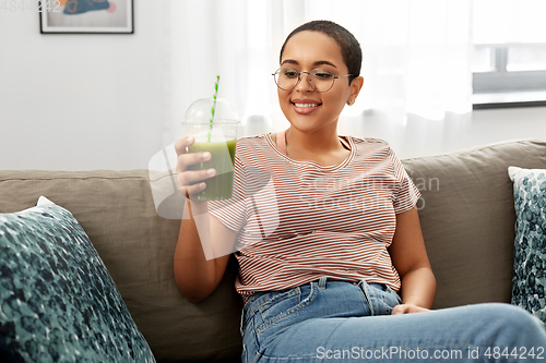 Image of african american woman drinking smoothie at home