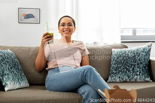 Image of african american woman drinking smoothie at home