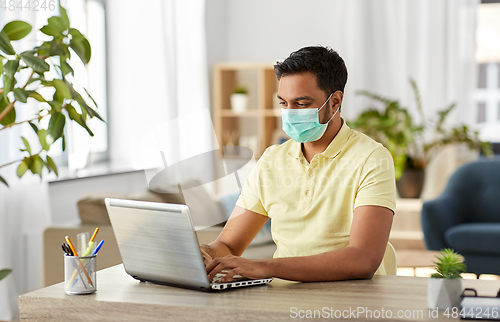 Image of indian man in mask with laptop at home office