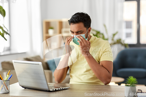 Image of indian man in mask with laptop at home office