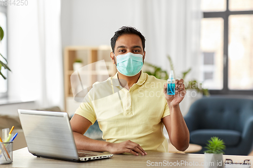 Image of man in mask with hand sanitizer at home office