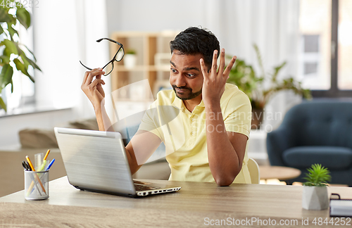 Image of stressed man with laptop working at home office