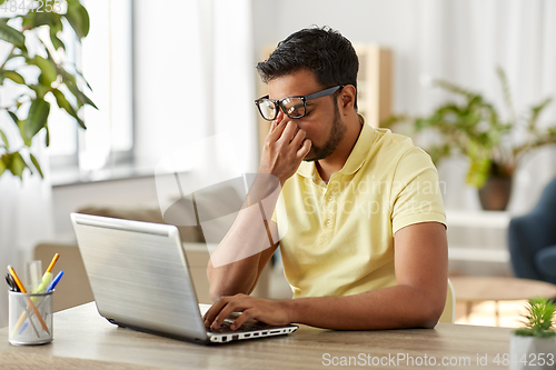 Image of tired man with laptop working at home office