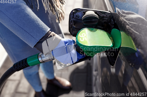 Image of close up of hand in glove filling car with petrol