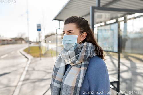 Image of young woman wearing medical mask at bus stop