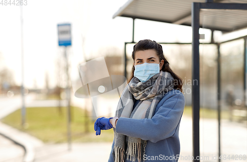 Image of woman in mask with wristwatch at bus stop