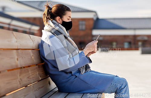 Image of woman in face mask with smartphone in city