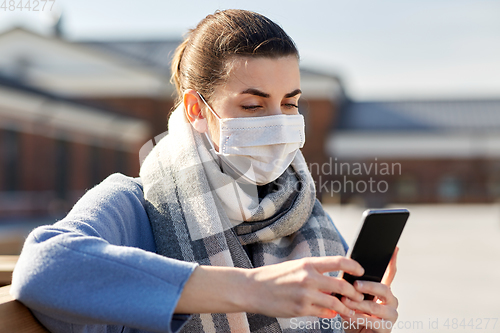 Image of woman in face mask with smartphone in city