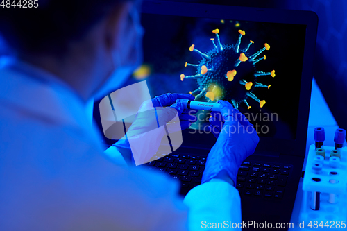 Image of hand holding beaker with coronavirus blood test