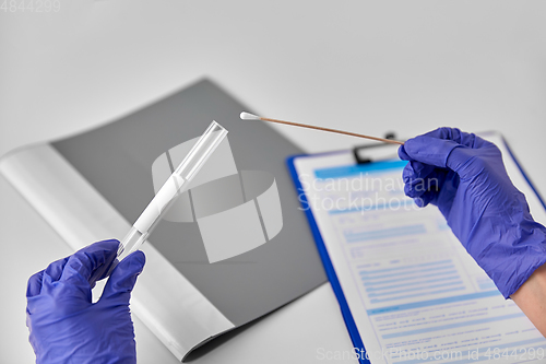 Image of hands in gloves holding test tube and cotton swab