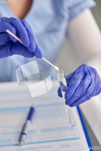 Image of hands in gloves holding test tube and cotton swab