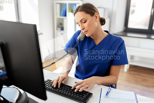 Image of doctor with computer calling on phone at hospital