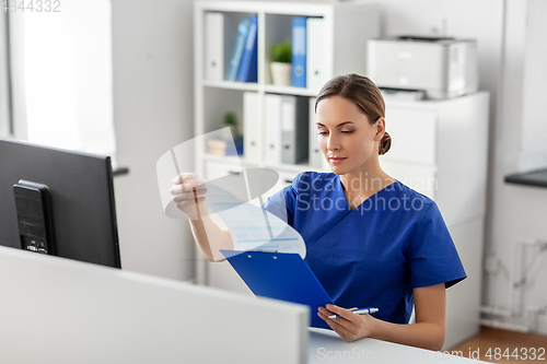 Image of doctor or nurse with clipboard working at hospital