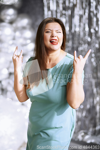 Image of Happy plus size woman showing rock and roll hand gesture