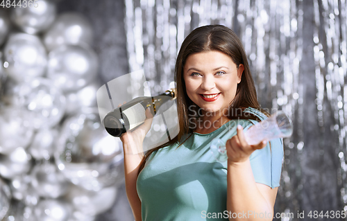 Image of Happy plus size woman holding wine bottle and glass