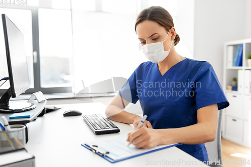 Image of doctor or nurse in mask with clipboard at hospital