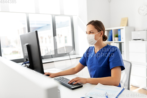 Image of doctor or nurse in mask with computer at hospital