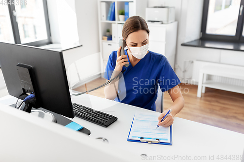 Image of doctor with computer calling on phone at hospital