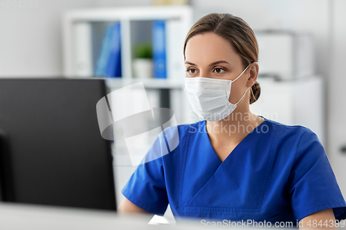 Image of doctor or nurse in mask with computer at hospital