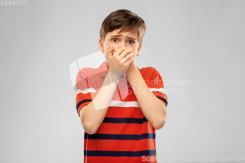 Image of scared boy clothing mouth with hands