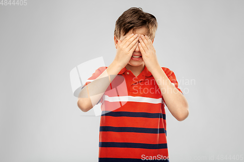 Image of scared boy closing eyes with hands