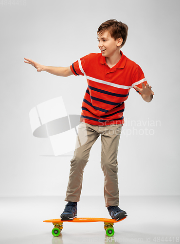 Image of smiling boy riding on short skateboard