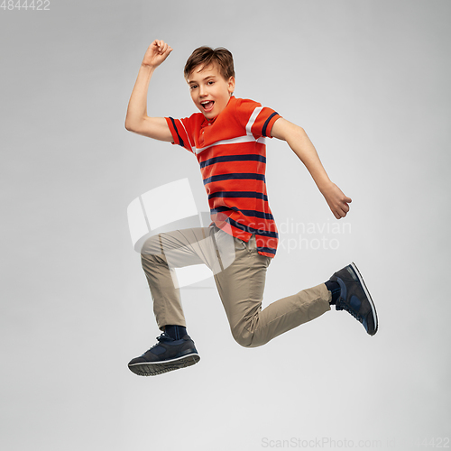 Image of happy smiling young boy jumping or running in air