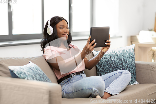 Image of woman with tablet pc listening to music at home