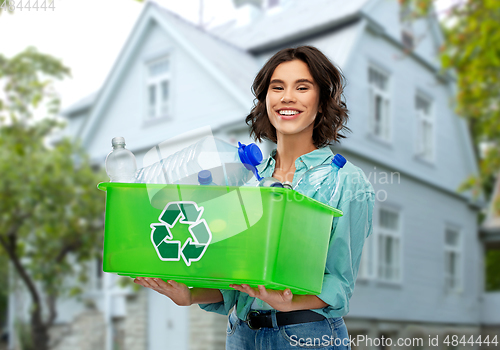 Image of smiling young woman sorting plastic waste outdoors