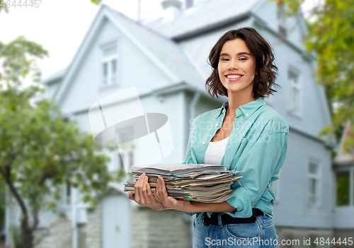 Image of smiling young woman sorting paper waste outdoors