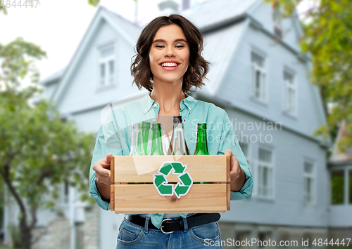 Image of smiling young woman sorting glass waste outdoors