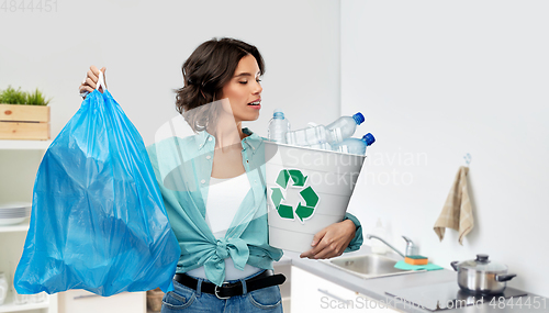 Image of smiling woman sorting plastic waste and trash bag