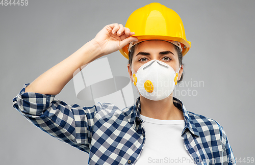 Image of female worker or builder in helmet and respirator