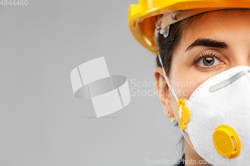 Image of female worker or builder in helmet and respirator