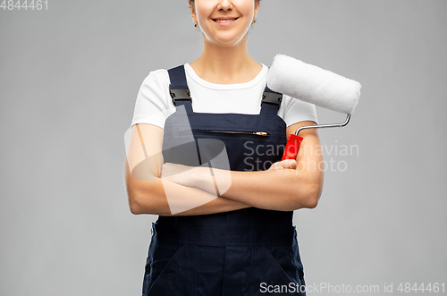 Image of happy female worker or builder with paint roller