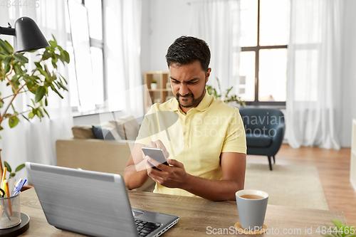 Image of indian man with smartphone at home office