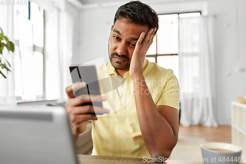 Image of indian man with smartphone at home office